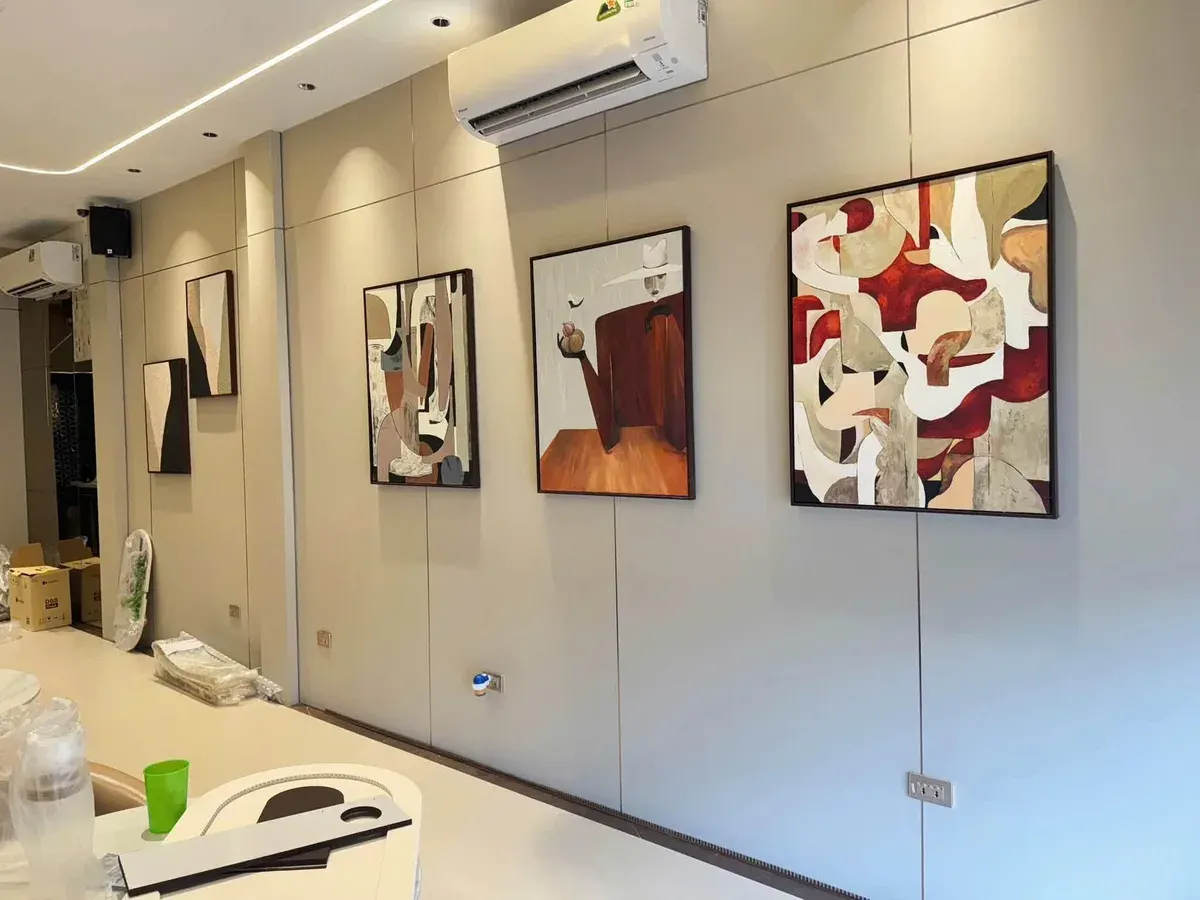 Tường phòng khách ốp tấm than tre Newhome màu be, treo tranh, công trình thực tế